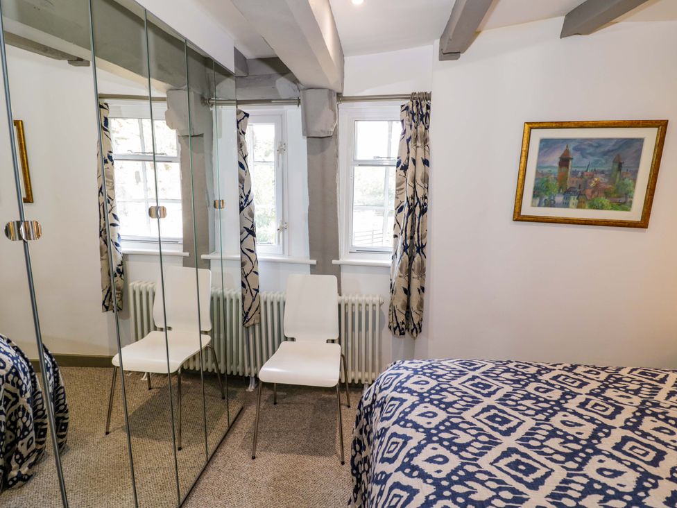 A bedroom with a bed, chair, and mirror at Middle Cottage in Ludlow