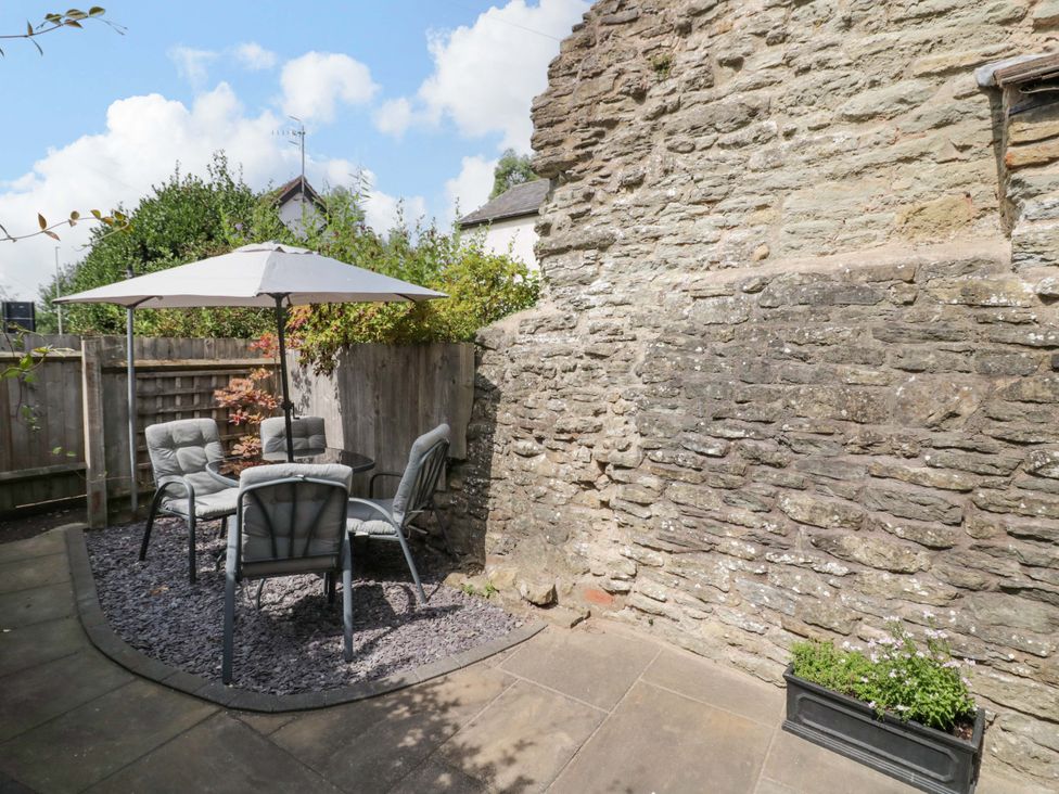 A garden with a table and chairs under an umbrella at Middle Cottage Ludlow