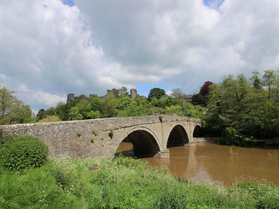 A stone bridge over a river with a castle in the background at Middle Cottage in Ludlow