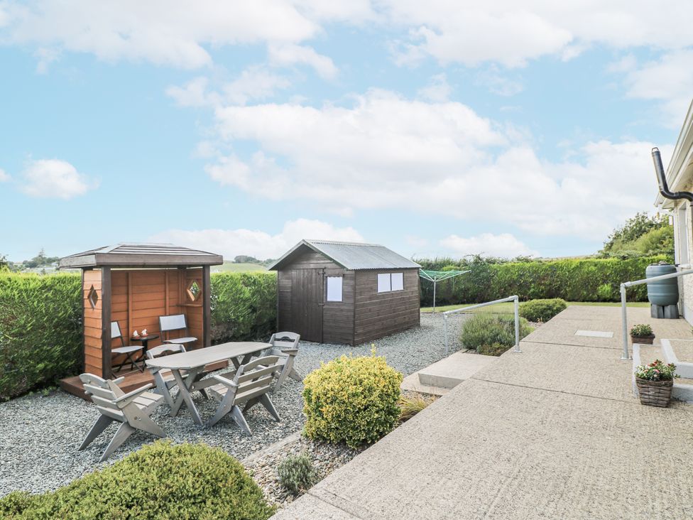A garden with a table and chairs near two outdoor sheds at Dunbrody Dreams