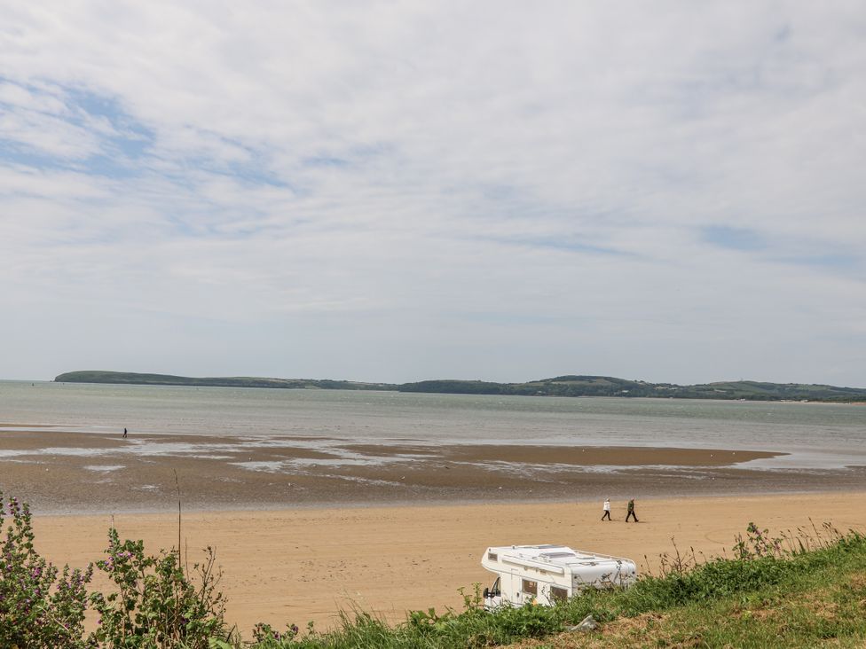 A beach with people walking and a caravan at Dunbrody Dreams