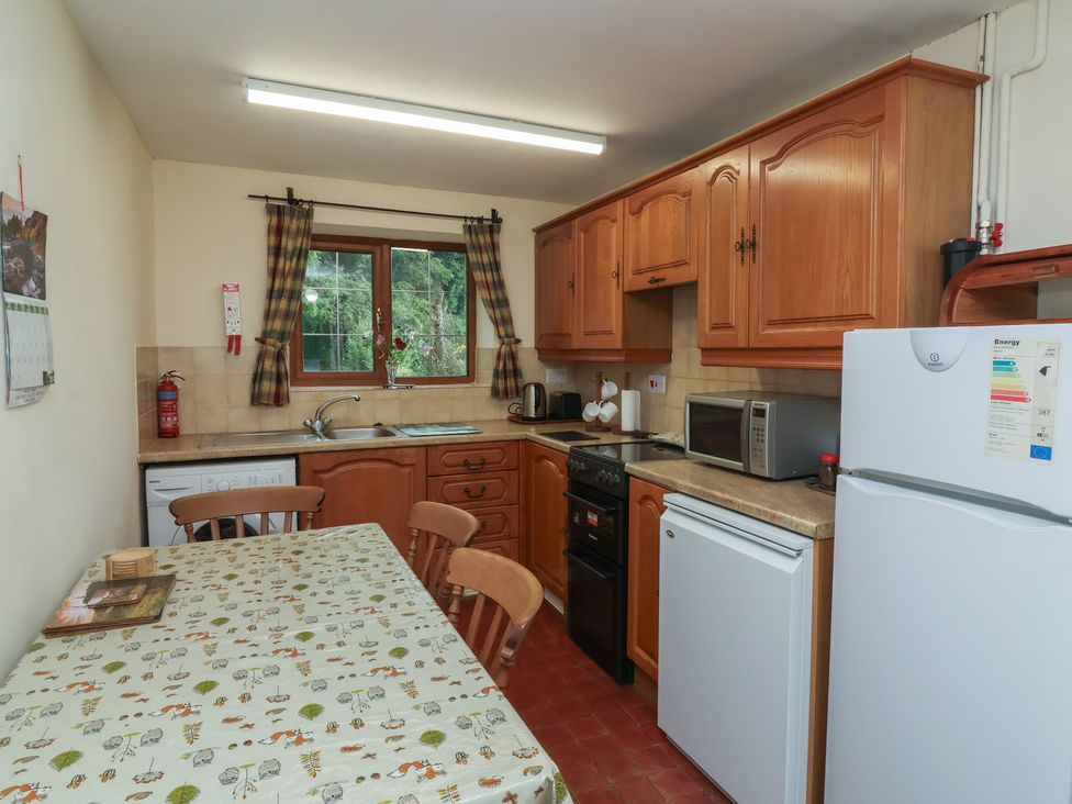 A kitchen with wooden cabinets and appliances at Denhill Cottage