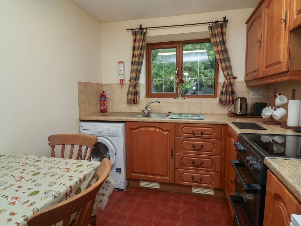 A kitchen with a table and washing machine at Denhill Cottage in 