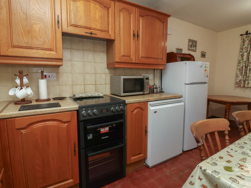 A kitchen with wooden cabinets and appliances at Denhill Cottage 