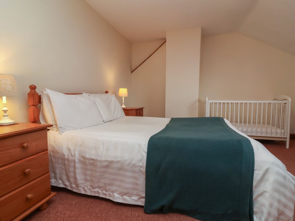 A bedroom with a bed and crib at Denhill Cottage