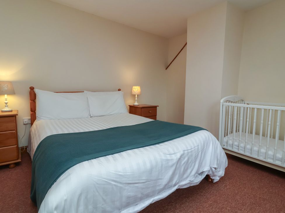 A bedroom with a bed and cot at Denhill Cottage