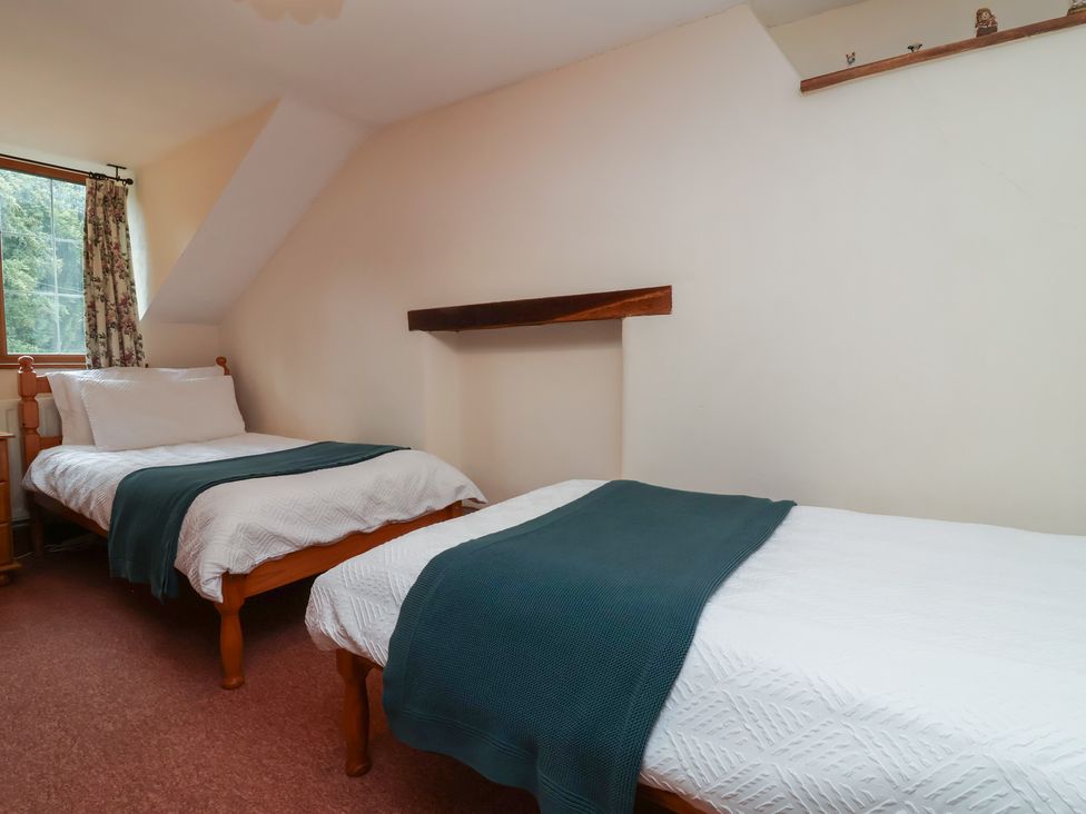 A bedroom with two beds and a window at Denhill Cottage 