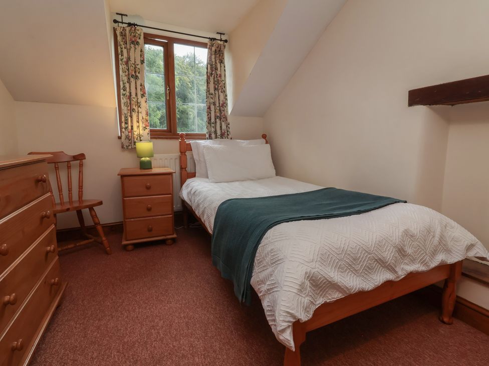 A bedroom with a single bed and wooden furniture at Denhill Cottage
