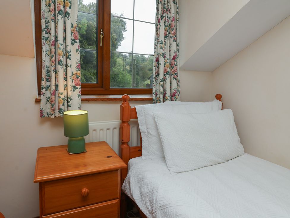 A bedroom with a bed and a nightstand at Denhill Cottage