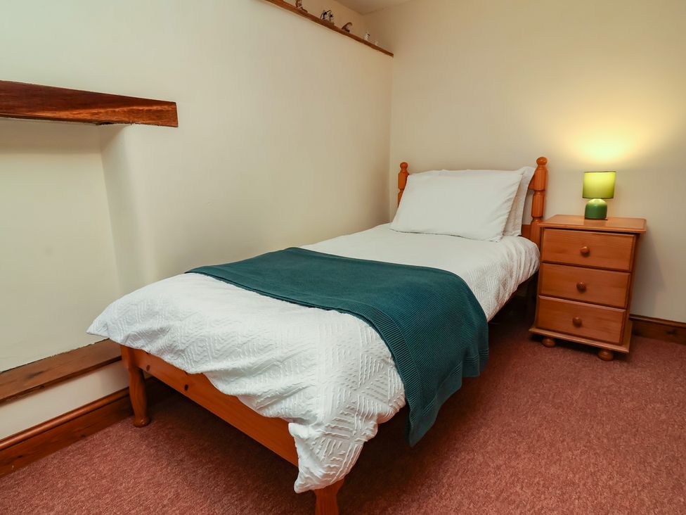 A bedroom with a bed and bedside table at Denhill Cottage