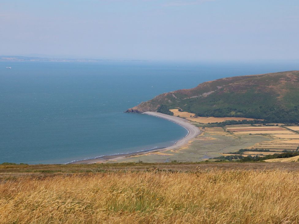 A coastline with a beach and hills overlooking the sea at Denhill Cottage