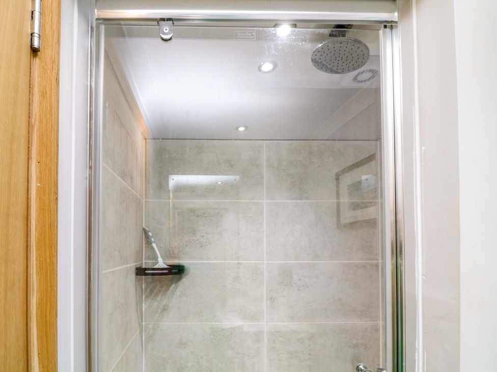 A shower area with wall tiles and a showerhead at Mylo's Cottage in Langrick near Boston
