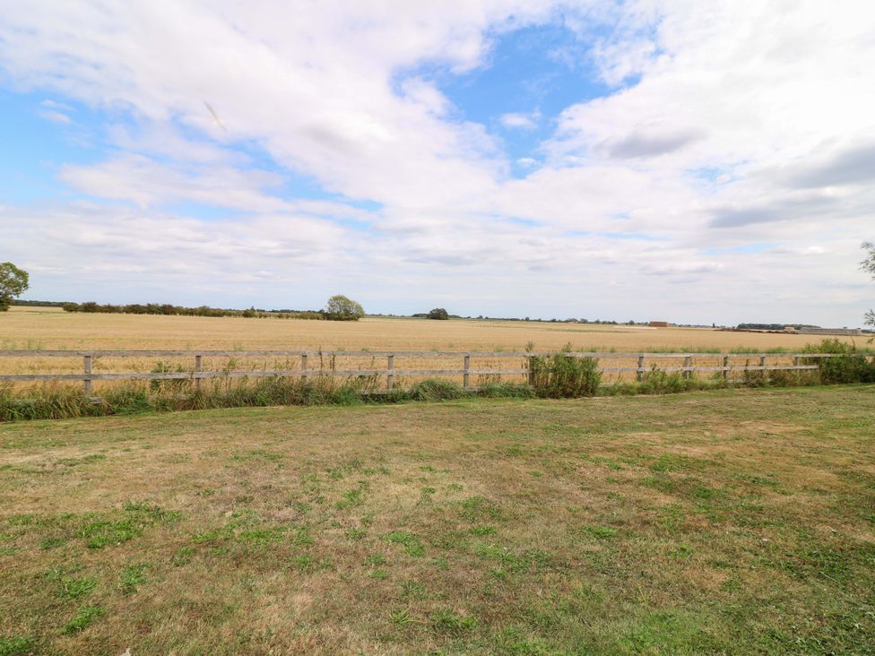 A field with a wooden fence and grass at Mylo's Cottage in Langrick near Boston