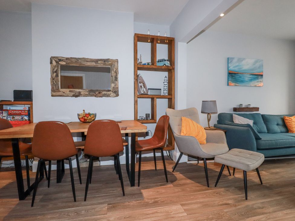 A dining area with a table and chairs adjacent to a living area at Sea Boots in Newquay