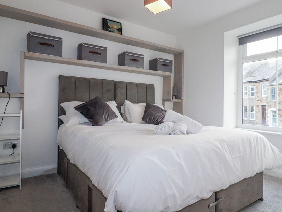 A bedroom with a bed and storage boxes on a shelf at Sea Boots in Newquay