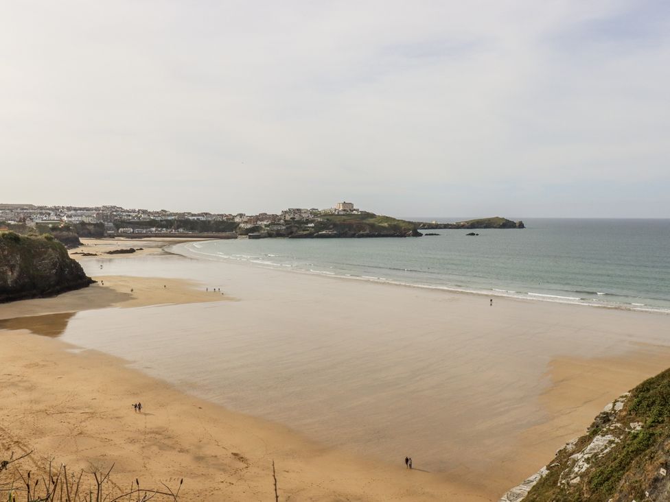 A beach view with people walking along the shore at Sea Boots in Newquay