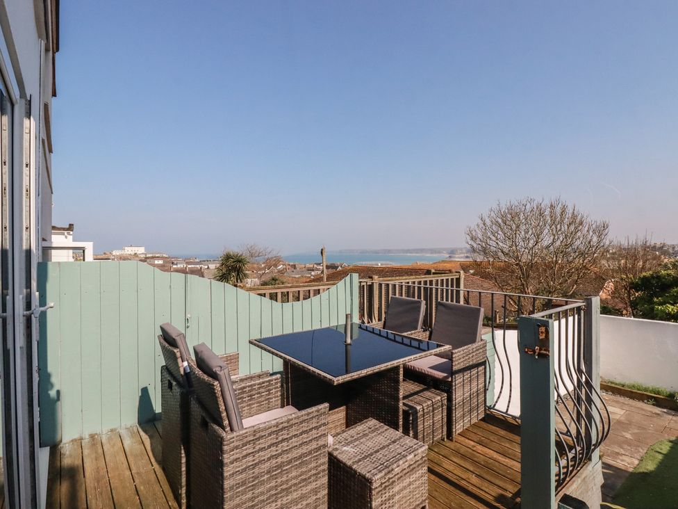 An outdoor seating area with a table and chairs overlooking the sea at Sea Boots in Newquay