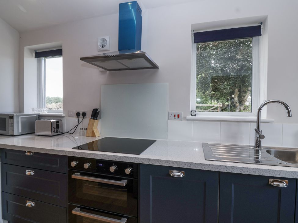 A kitchen with a sink, cooker, and microwave at The Miners Cottage in Wells