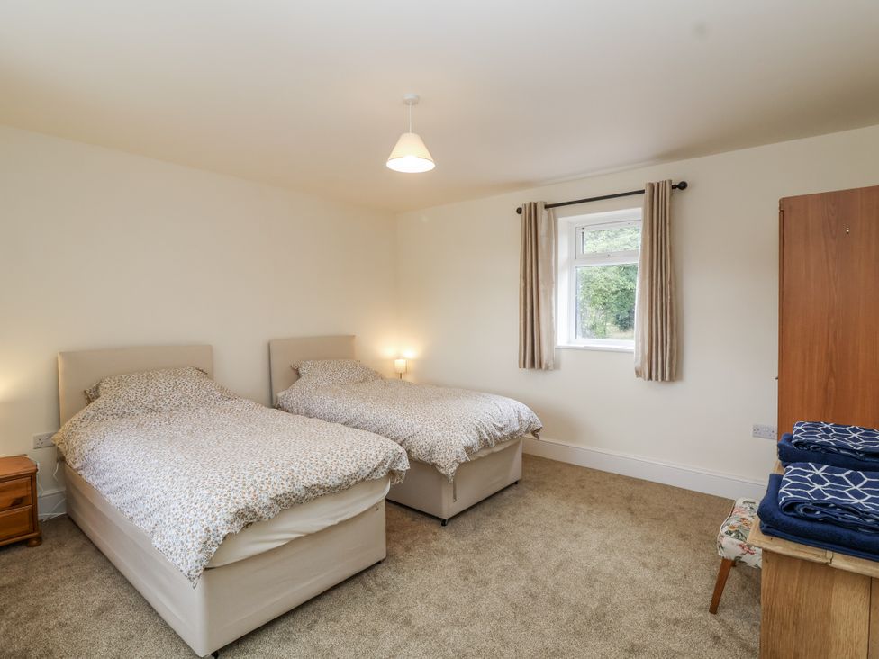 A bedroom with two beds and a window at The Miners Cottage in Wells