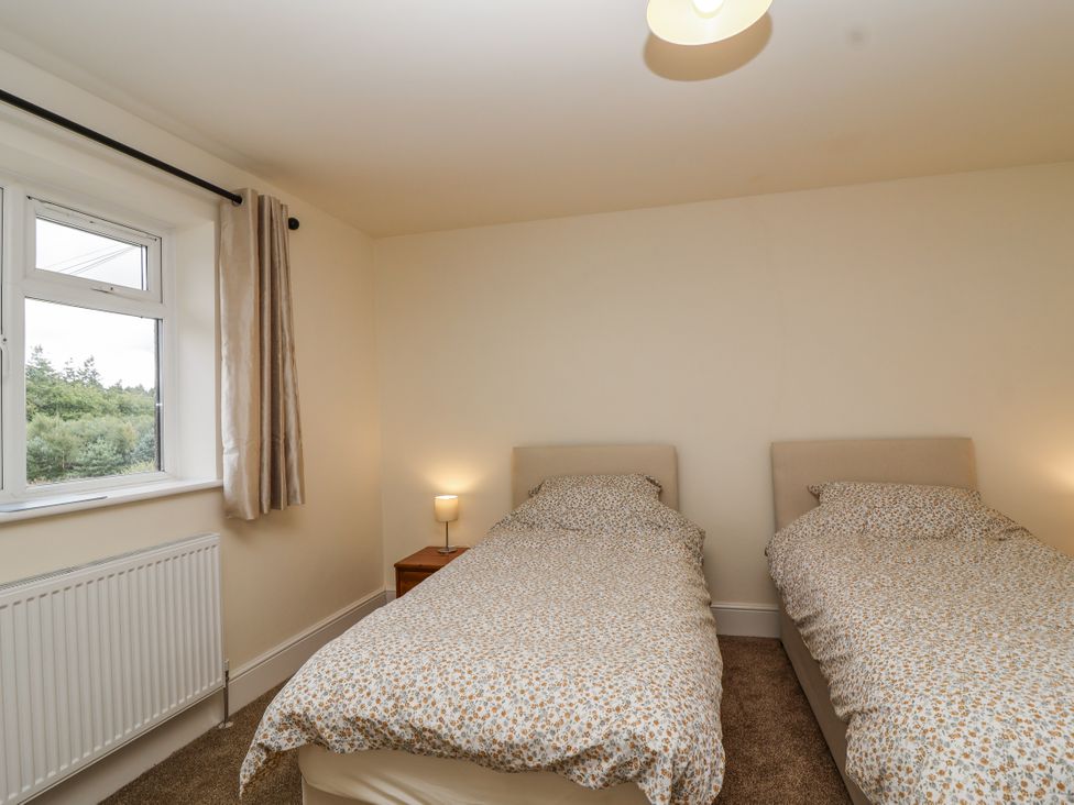 A bedroom with two beds and a window at The Miners Cottage in Wells