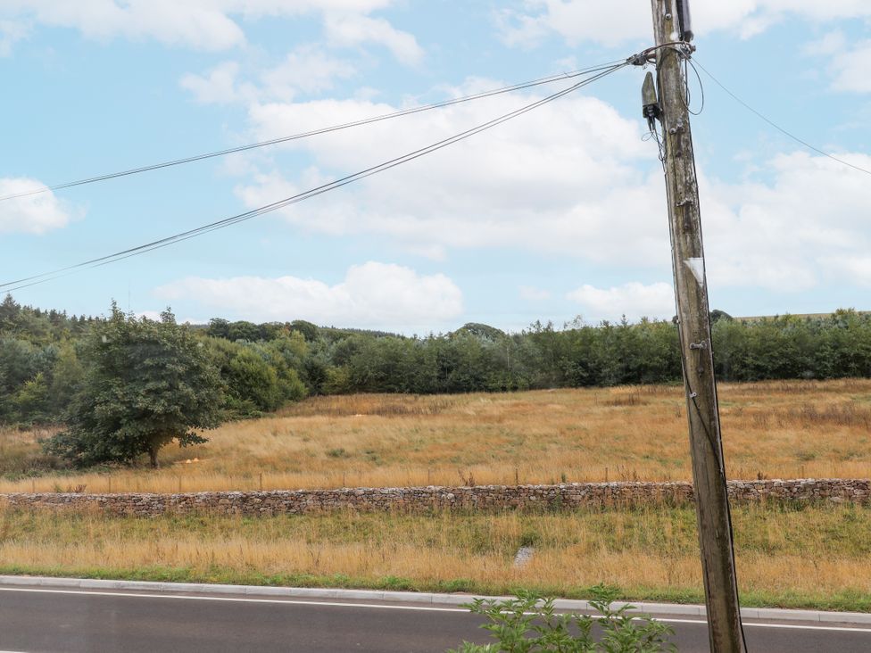 A view of a field with a telephone pole and stone wall at The Miners Cottage in Wells