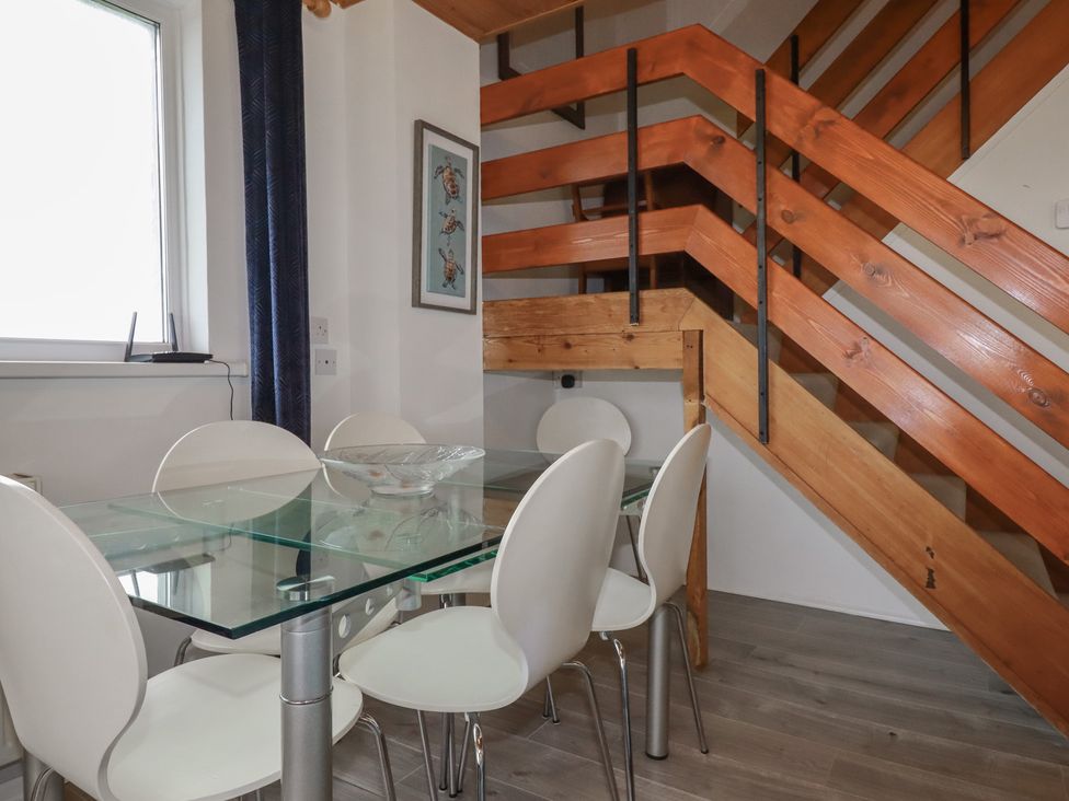 A dining room with a glass table and plastic chairs at 38 Surf View in Newquay