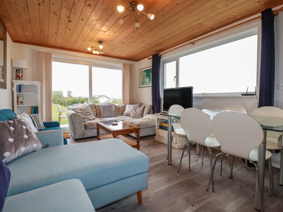 A living room with a sofa and a dining area at 38 Surf View in Newquay