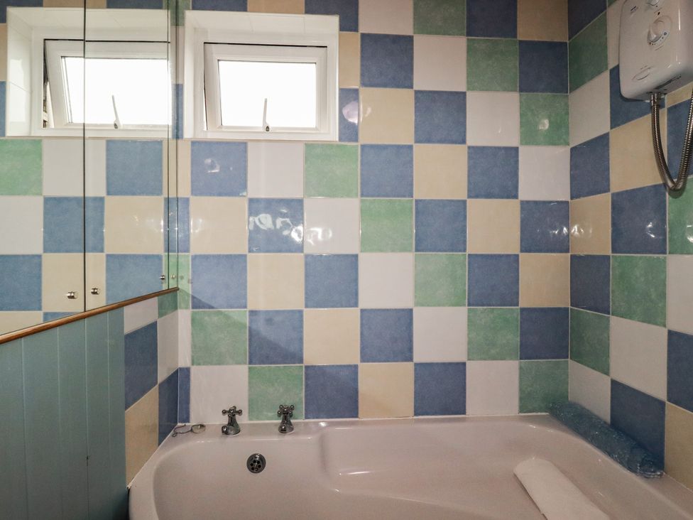 A bathroom with a bathtub and tiled walls at 38 Surf View Newquay
