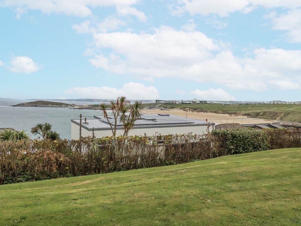 View of ocean and beach with green grass and building at Surf View in Newquay