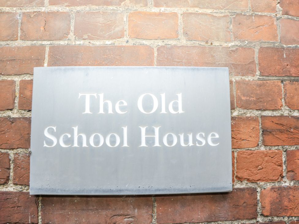 A sign displaying The Old School House on a brick wall in Windsor