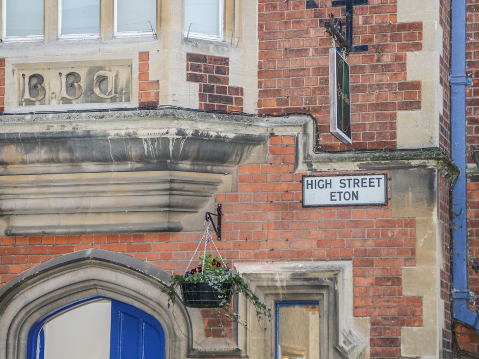 A brick building with a sign reading 'High Street Eton' and a planter at The Old School House in Windsor