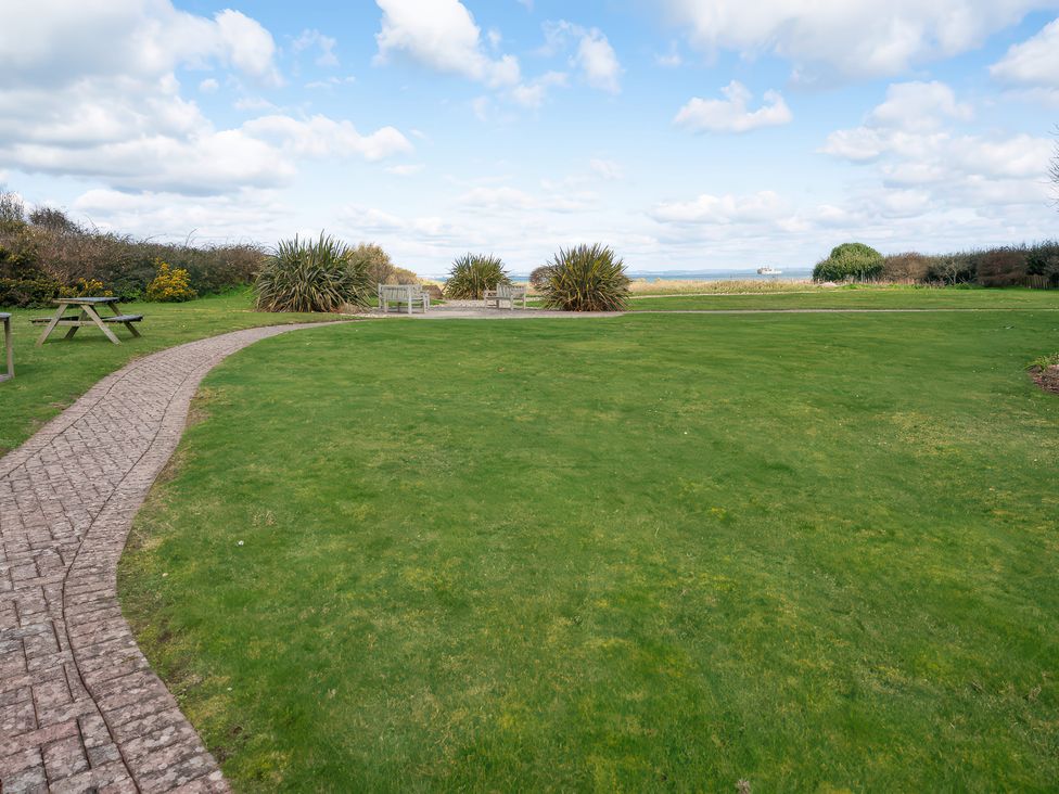 A garden with pathways and benches at 17 Solent Landing, Bembridge