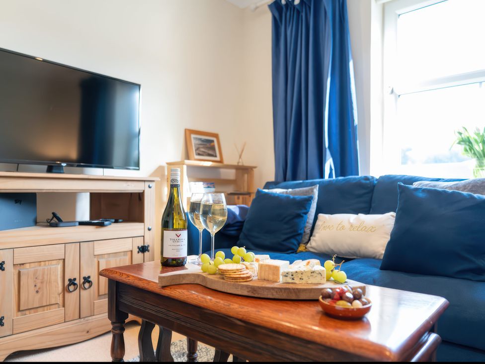 A living room with a television and wine on a table at 17 Solent Landing in Bembridge