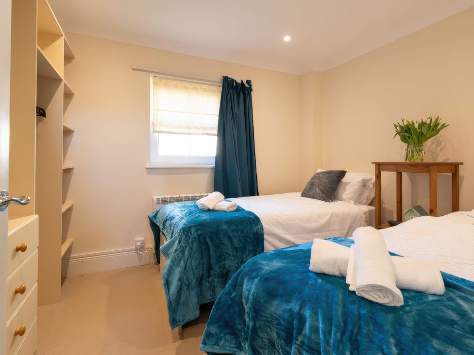 A bedroom with two beds and a bedside table at 17 Solent Landing in Bembridge