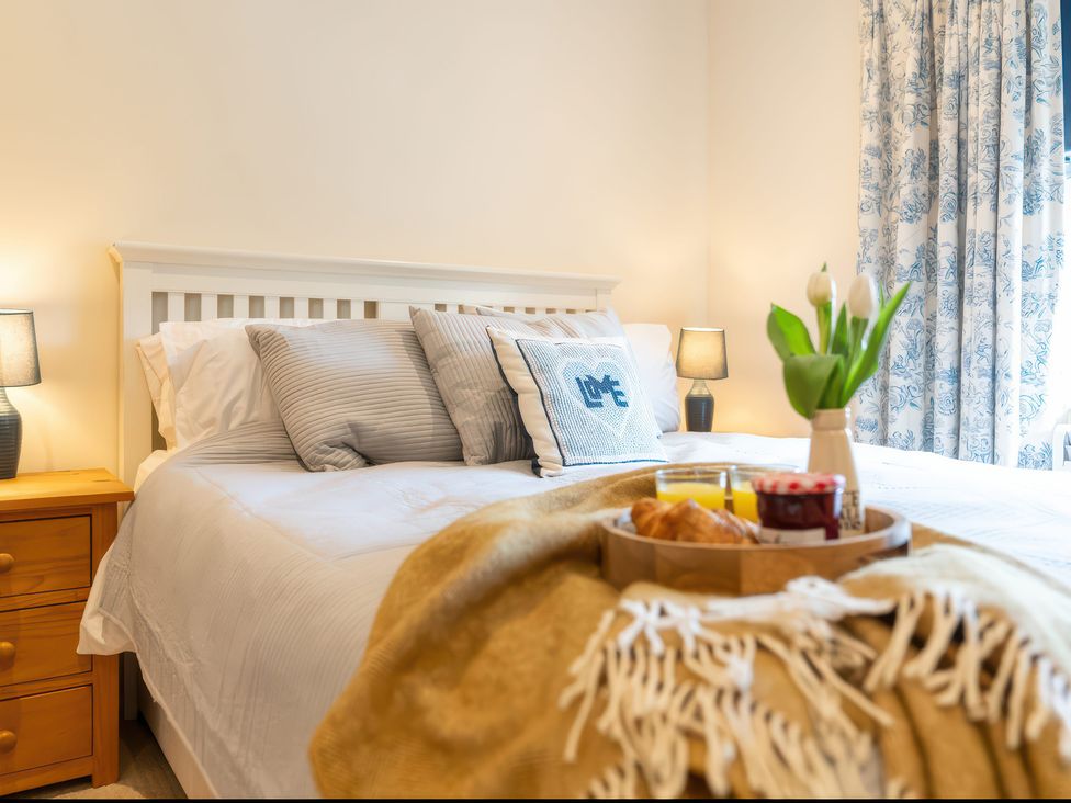 A bedroom with bed, nightstand and breakfast tray at 17 Solent Landing in Bembridge