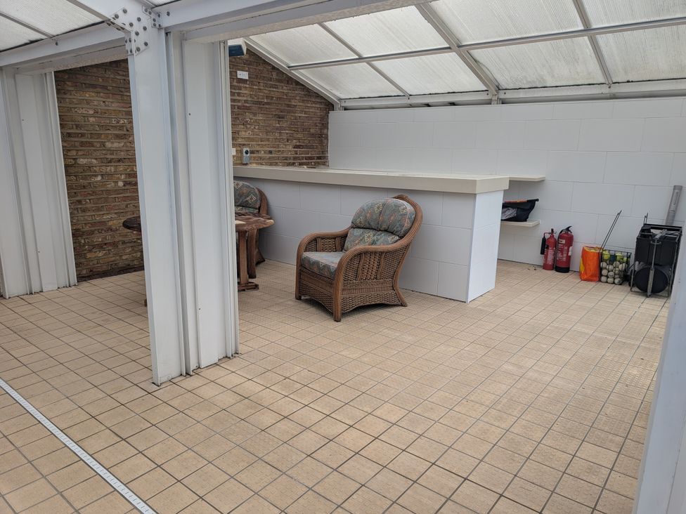 A conservatory with seating and a bar at Heath Lodge in Iver