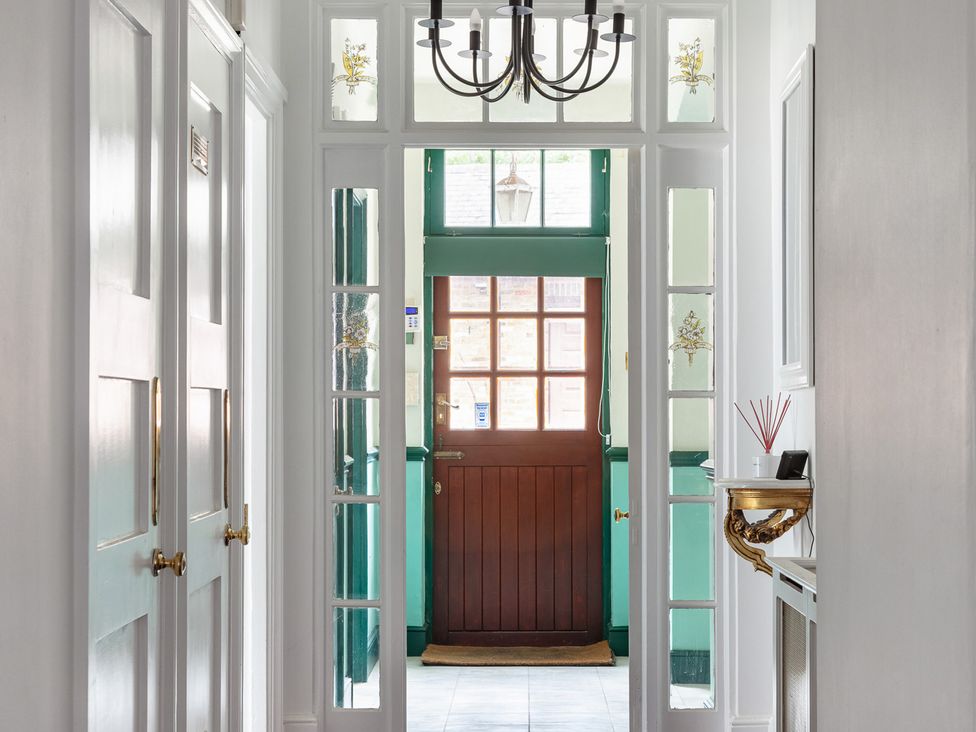 A hallway with a front door and chandelier at Violet House in Iver