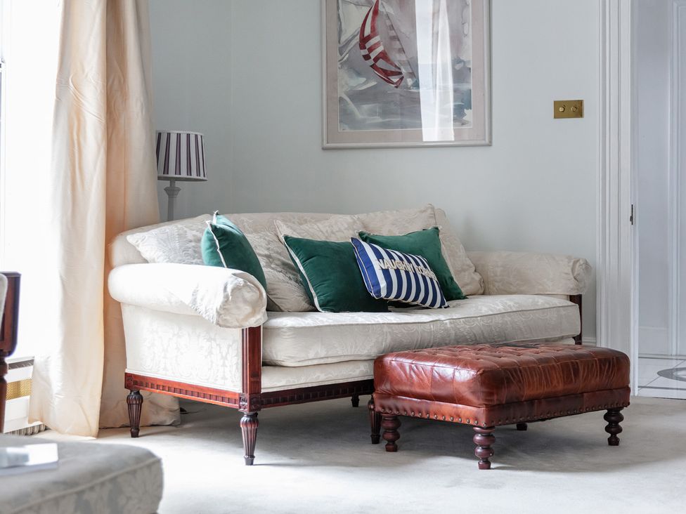 A living room with a sofa and ottoman at Violet House in Iver