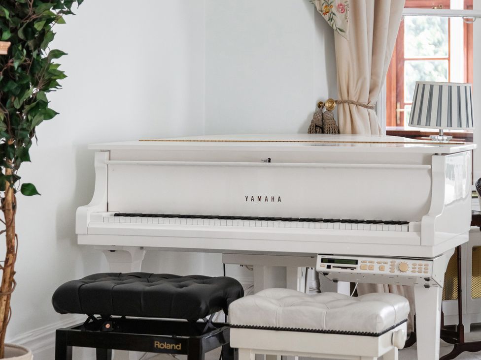 A Yamaha piano with benches and a plant at Violet House in Iver