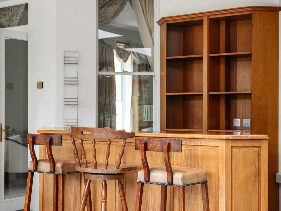 A kitchen with bar area and wooden shelves at Violet House in Iver