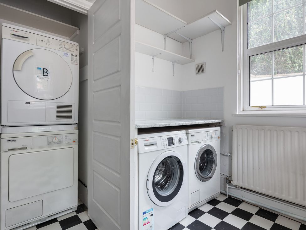 A laundry room with washing machines and a tumble dryer at Violet House in Iver