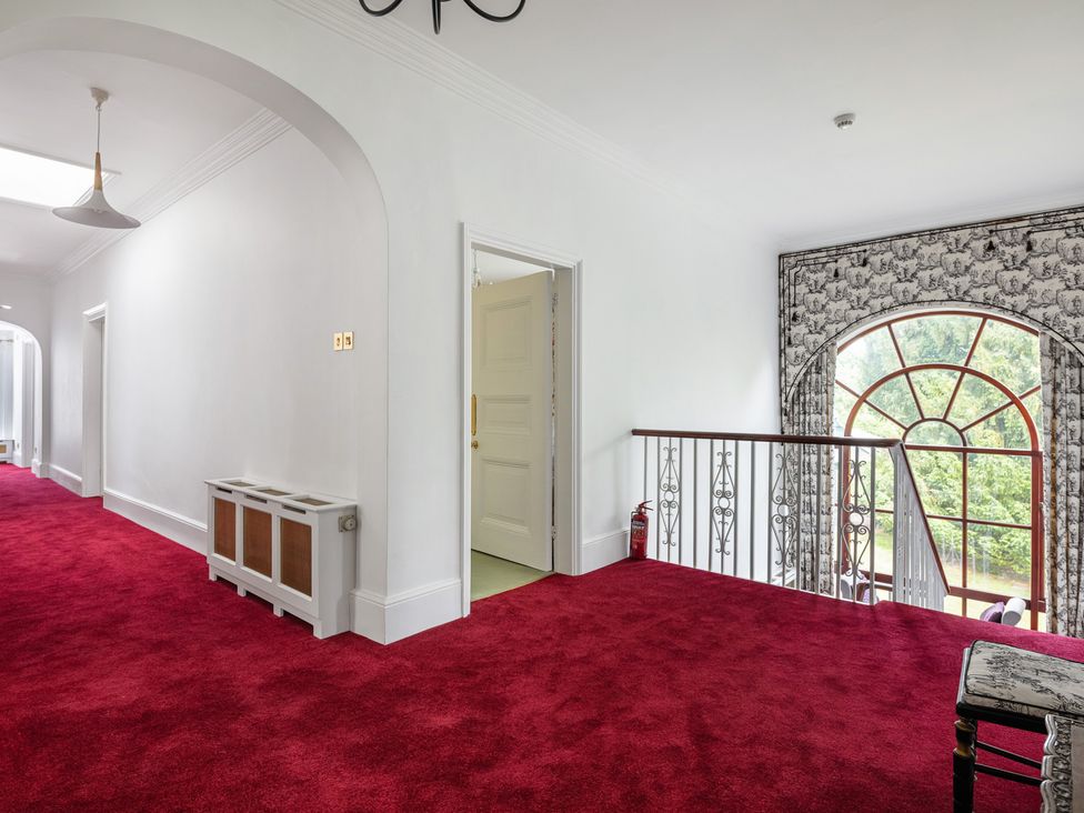 A hallway with a red carpet and a window at Violet House in Iver