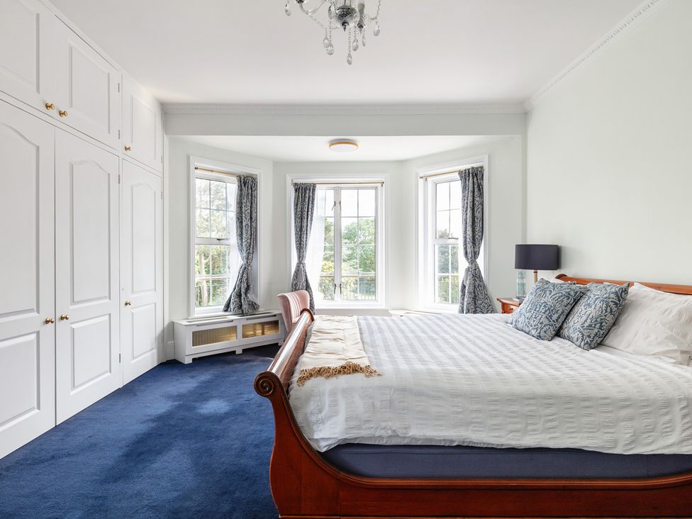 A bedroom with a bed and windows at Violet House in Iver
