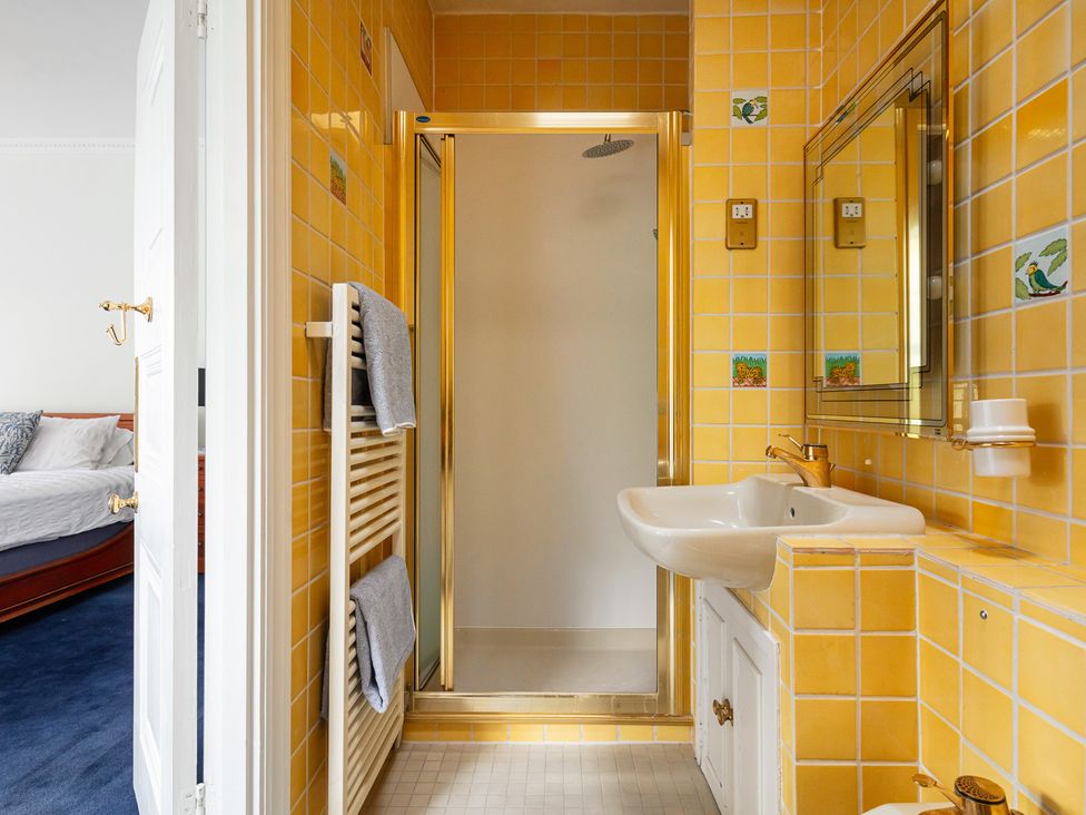 A bathroom with yellow tiles and a shower at Violet House in Iver