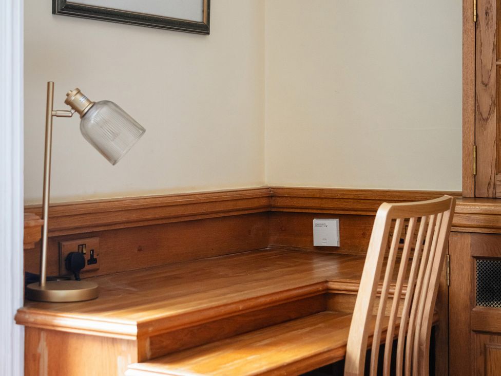 A home office with a wooden desk and lamp at Violet House in Iver