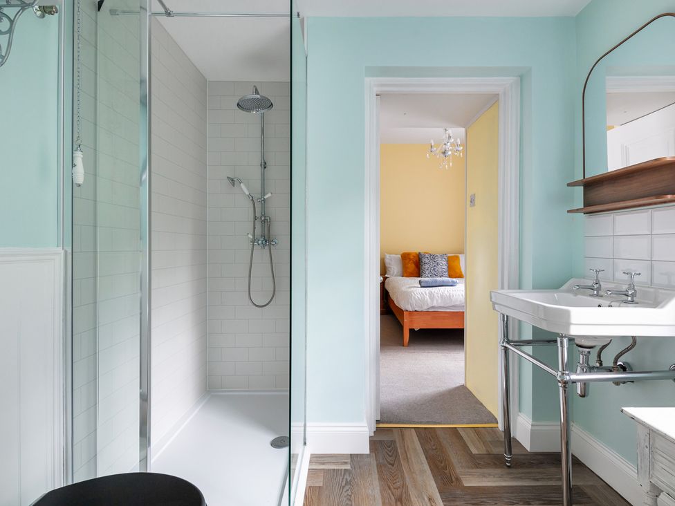 A bathroom with a shower and sink leading to a bedroom at Violet House in Iver
