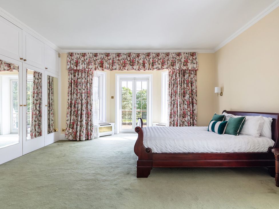 A bedroom featuring a bed with pillows and curtains at Violet House in Iver