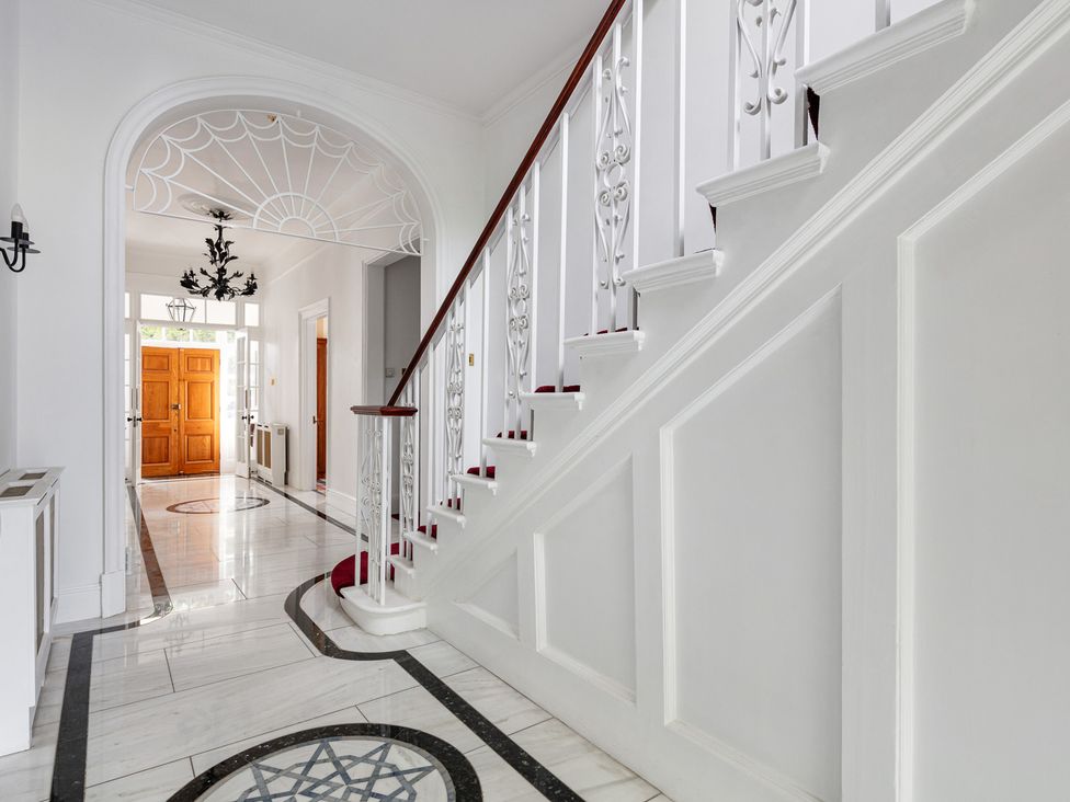 A hallway with a staircase and chandelier at Violet House in Iver