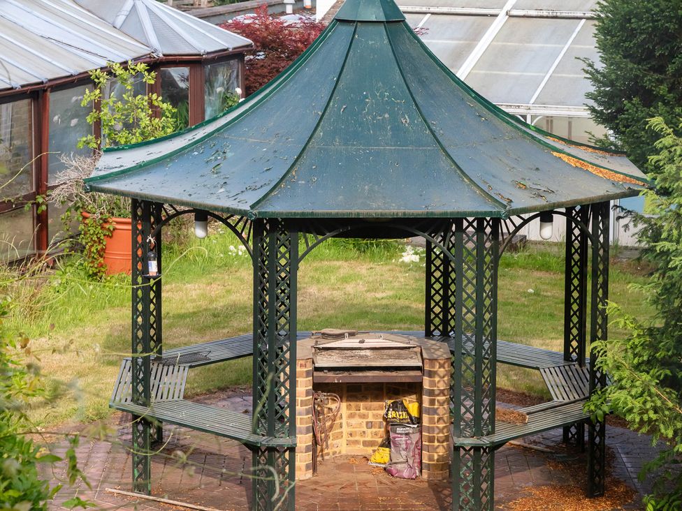 A gazebo with benches and a grill at Violet House in Iver