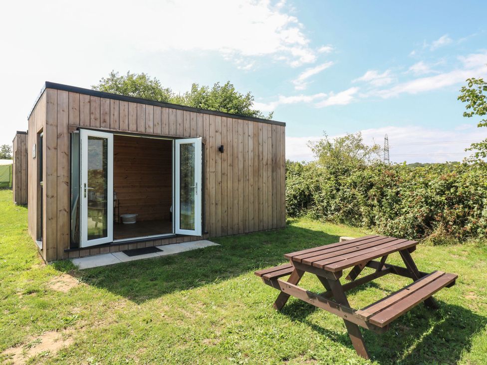 A wooden cabin with a picnic table outside at Bluebell Lodge in Hastings